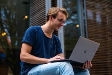 Mann sitzt und schaut in einen Laptop