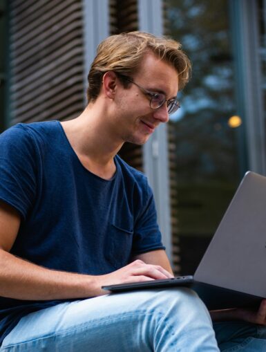 Mann sitzt und schaut in einen Laptop