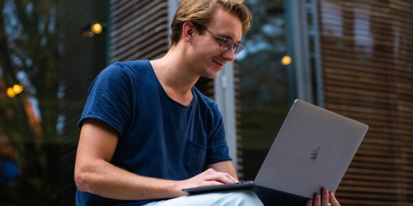 Mann sitzt und schaut in einen Laptop