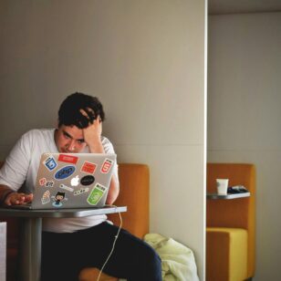 junger Student schaut verzweifelt in den Laptop